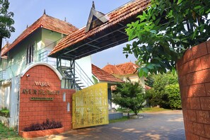 A building with a red-tiled roof, a sign reading "Vajra Ayur Retreat," and a decorative gate.