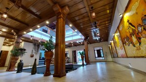 A spacious lobby with high ceilings, wooden beams, and a large mural.