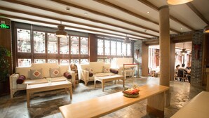 Eine großzügige Lobby mit Holzbänken, einem zentralen Tisch mit Früchten und großen Fenstern, die natürliches Licht hereinlassen.