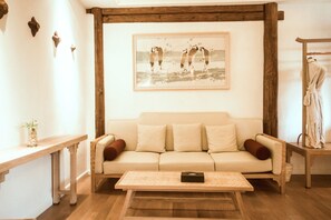 Een knusse woonkamer met een bank, een bijzettafeltje en een schilderij van vogels aan de muur.