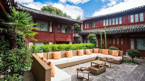 Ein traditioneller Innenhof mit einer großen, gebogenen Couch und einem kleinen runden Tisch.