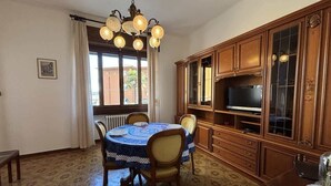 A dining area with a round table, chairs, a chandelier, wooden cabinets, and a television. - Apartment few steps from the lake - Larihome A16 (Dongo)