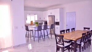 Una cucina moderna con mobili bianchi, un tavolo da pranzo in legno e sedie nere.