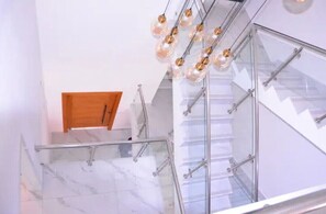 A modern staircase with glass railings and a wooden door at the top.