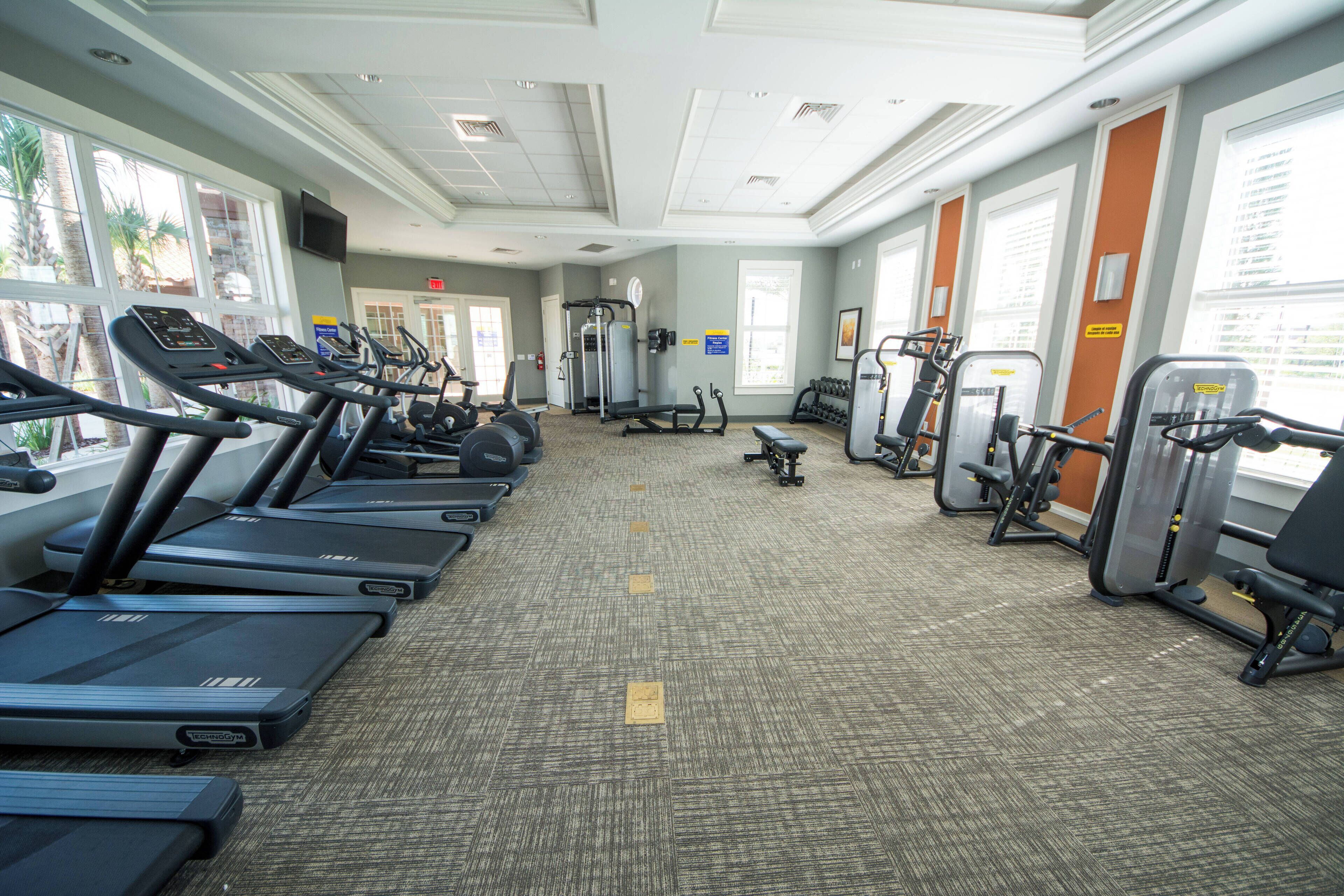 A gym with treadmills, weight machines, and exercise mats.