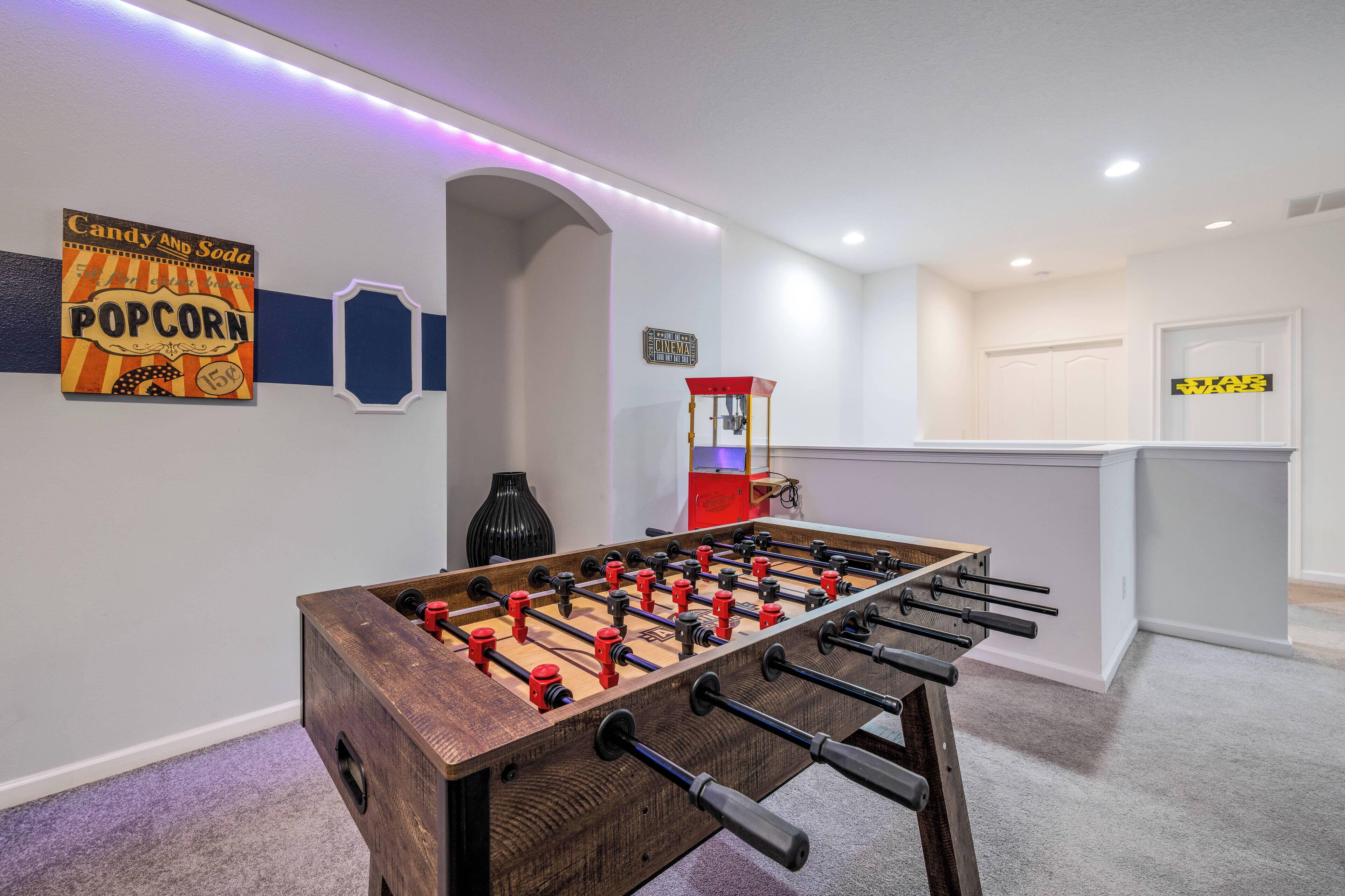 A room with a foosball table, a popcorn sign, and a Star Wars sign.