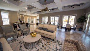 Un salon spacieux avec un canapé beige, une table basse ronde et un tapis à motifs.