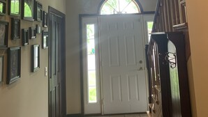 A hallway with a white door, multiple framed pictures on the walls, and a staircase on the right. - Premier Host-Tetonka & Sakatah Lakes Dock, Kayaks, Lakeside Fire Pit & Gameroom (Waterville)