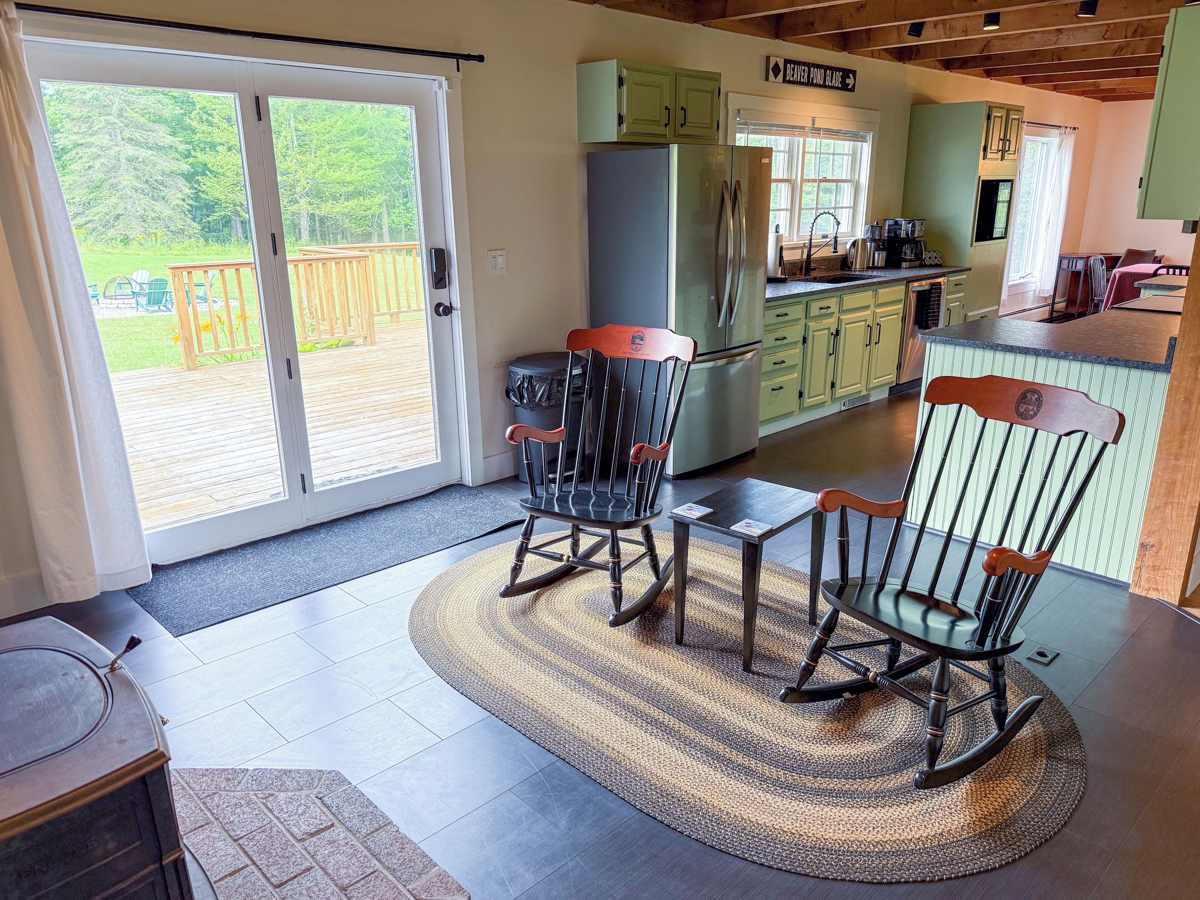 A kitchen with a refrigerator, cabinets, and a dining area with chairs.