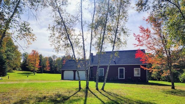 A house with a red exterior, surrounded by a grassy yard and trees with autumn foliage. - Private 10-Acre Lodge Near Jay Peak + Fire Pit (Troy)