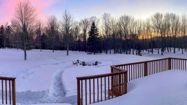A snow-covered outdoor area with a wooden deck and a fire pit.