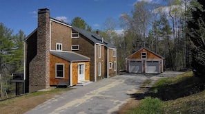Stunning two-story home with a brick chimney and sloped roof, set amidst a tranquil wooded backdrop.