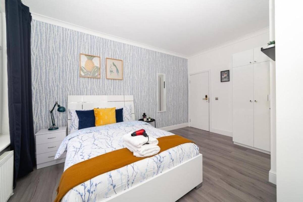 Een slaapkamer met een bed, nachtkastjes, een dressoir en een kledingkast.