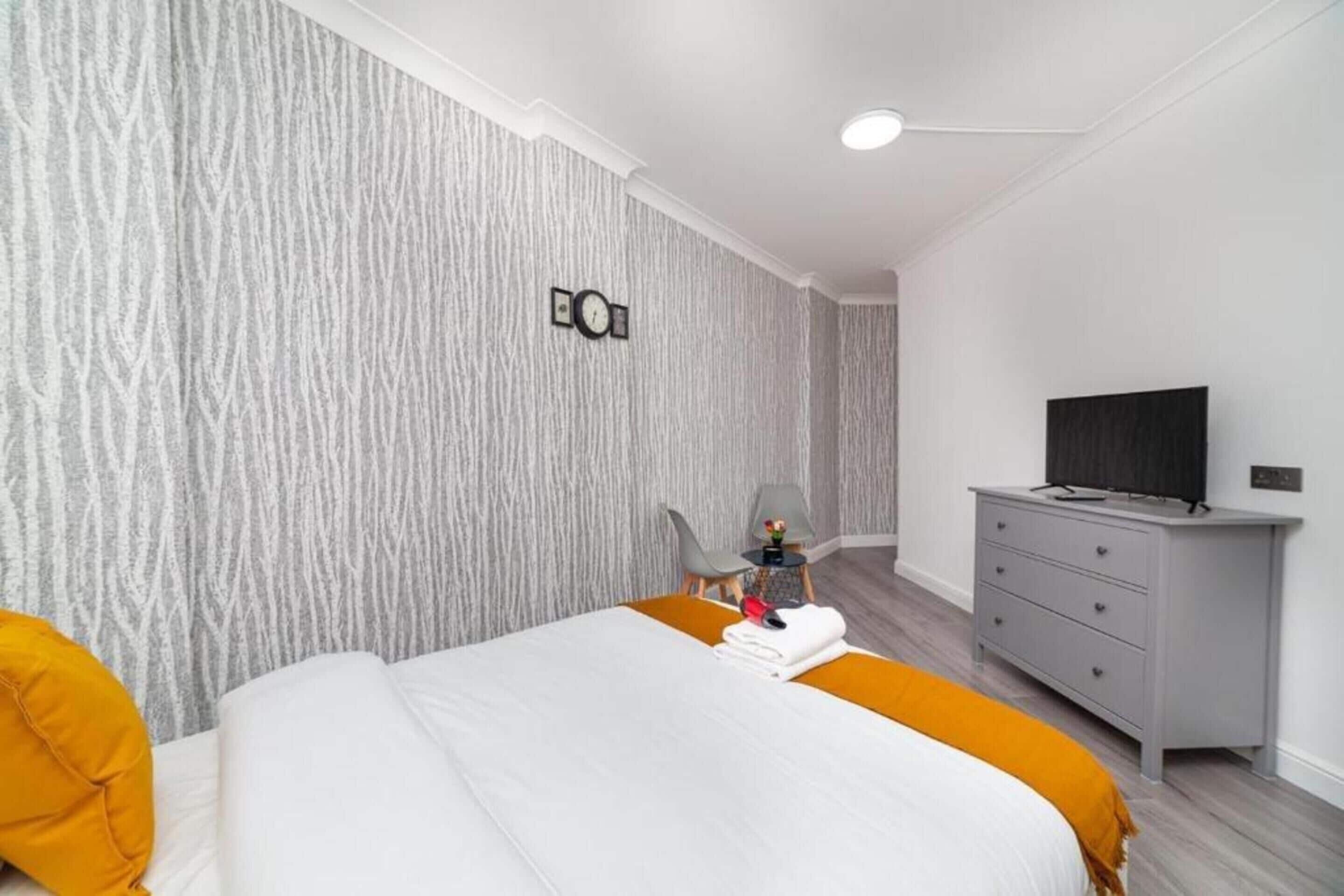 Quarto de hotel moderno com uma cama grande, televisão, escrivaninha e uma cadeira.