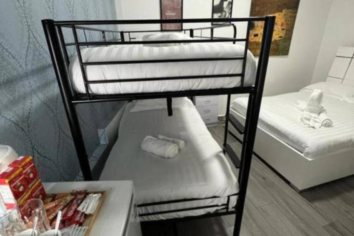 Een slaapkamer met een stapelbed, een tafeltje, een doos lekkernijen en een schilderij aan de muur.