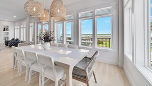 A spacious dining area with a large table, white chairs, and wicker pendant lights. - PRIVATE LUXURY HOUSE, COMMUNITY POOL, WATERFRONT ON LITTLE LAGOON! (Gulf Shores)