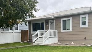 A single-story house with a front porch, a small staircase, and a well-maintained lawn.