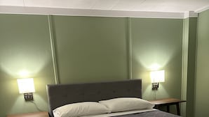 A bed with a grey headboard, two bedside tables, and two wall-mounted lamps. - Downtown Meredith Village Cape (Meredith)