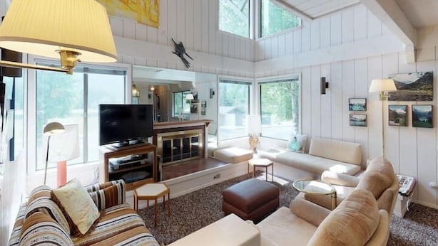 A spacious living room with a large TV, comfortable seating, and a fireplace. - Retro 3BD Sun Valley Condo + FREE Resort Amenities! (Sun Valley)