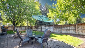 Une terrasse avec une table et des chaises, un barbecue et une clôture en bois.