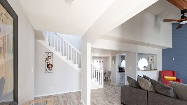 A spacious living area with a staircase, a grey sofa, and a red chair. - 3 BR by Mabee Center ORU, Casino, Jenks, Victory Church (Tulsa)