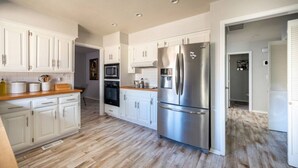 A modern kitchen with white cabinets, stainless steel appliances, and a wooden countertop. - 3 BR by Mabee Center ORU, Casino, Jenks, Victory Church (Tulsa)