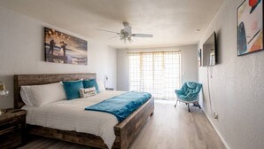 A bedroom with a wooden bed, a ceiling fan, a window with curtains, and a chair. - 3 BR by Mabee Center ORU, Casino, Jenks, Victory Church (Tulsa)