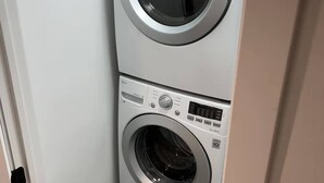Een kleine wasruimte met een wasmachine met bovenin een opening en een wasdroger met een vooropening.