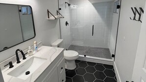 Een moderne badkamer met een wit wastafel, toilet en douchegedeelte.