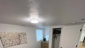 Een slaapkamer met een bed, kussens, een schilderij, een dressoir en een inloopkast.
