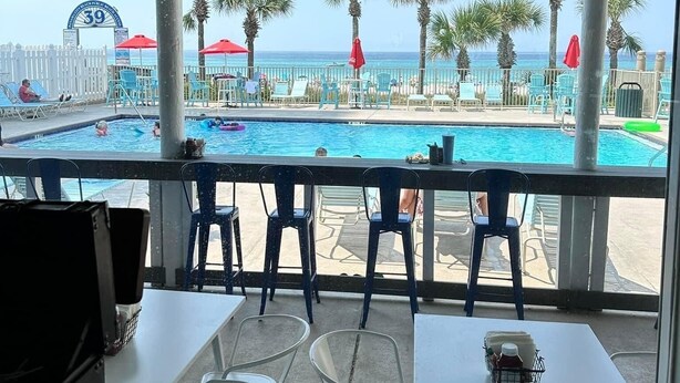 Ein Poolbereich mit Blick auf das Meer, Sitzgelegenheiten im Freien und ein Schild mit der Nummer 39.