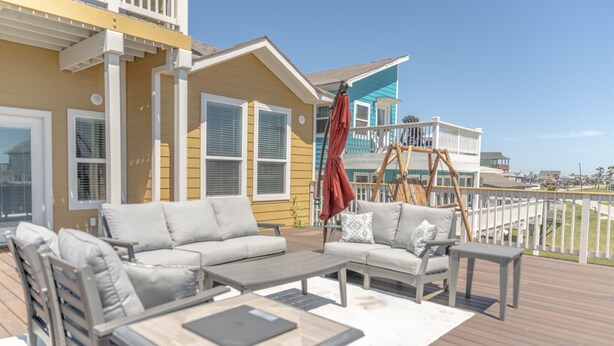 Une terrasse aménagée avec du mobilier d’extérieur, notamment un canapé, des chaises et une table.