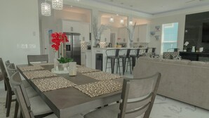 Une cuisine moderne avec des meubles blancs, un îlot central et des luminaires suspendus.