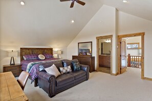 A bedroom with a bed, a leather sofa, a wooden dresser, and a balcony with a railing. - Large Bedroom Suites - Comm Hot Tub - On Ski Bus Line (Steamboat Springs)
