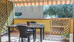 A patio with a table and chairs, a potted plant, and a view of a building and trees. - S305 - Sirolo, delightful apartment with porch (Sirolo)