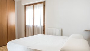 A bedroom with a bed, a wooden wardrobe, and a window with curtains. - S305 - Sirolo, delightful apartment with porch (Sirolo)