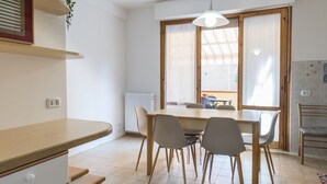 A dining area with a wooden table and chairs, a radiator, and a window with a view. - S305 - Sirolo, delightful apartment with porch (Sirolo)