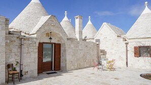 A stone building with multiple conical roofs, a wooden door, and outdoor seating.