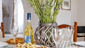 A dining table with a bottle of wine, a basket of herbs, and plates of food.