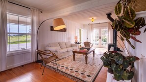 Una sala de estar acogedora con un sofá, sillas, una mesita de centro y una planta grande.