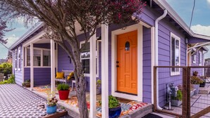 Una casa con porche, puerta de madera y plantas en macetas.