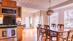 Una cocina moderna con electrodomésticos de acero inoxidable, armarios de madera y un comedor con una gran mesa y sillas de madera.