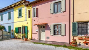 A row of colorful houses with distinct architectural styles, a gravel driveway, and potted plants.