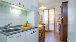 A kitchen with a sink, cabinets, a dining area with a table and chairs, and a patterned wall.