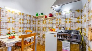A kitchen with a dining table, chairs, a refrigerator, a stove, and a tiled backsplash.