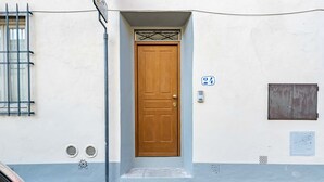 En byggnad med en trädörr, en skylt med nummer 24, ett fönster med galler och en liten ventilationsöppning.
