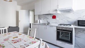 Ett modernt kök med vita skåp, en gasspis, en ugn och en mikrovågsugn.