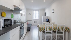 A compact kitchen with modern appliances, a dining area with a checkered tablecloth, and a window providing natural light.