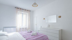 A bedroom with a bed, a dresser, a mirror, and a window with curtains.