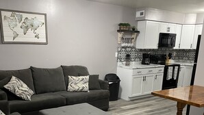 Un salon moderne avec un canapé gris, un pouf et une table basse en bois.